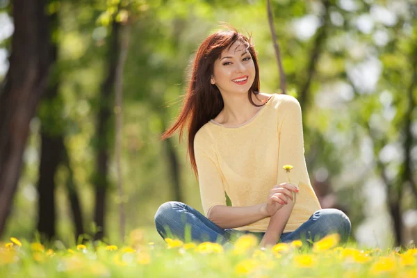 Junge glückliche Frau im Park mit Blumen — Stockfoto
