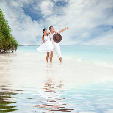 Young couple on the beach of sea clipart