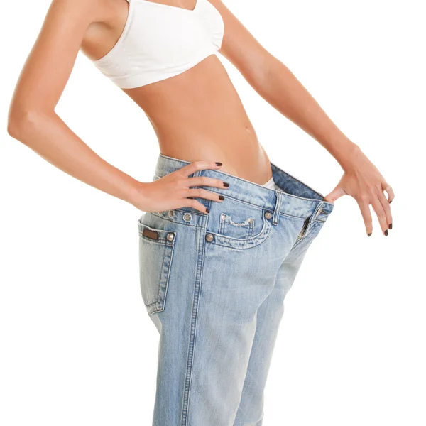 Frau zeigt ihren Gewichtsverlust, indem sie eine alte Jeans trägt — Stockfoto