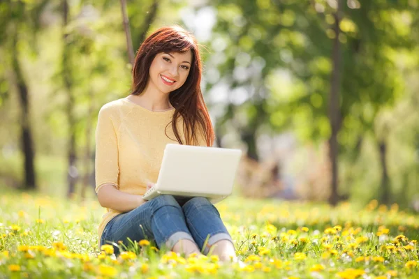 在公园的蒲公英白色笔记本电脑的可爱女人 — 图库照片