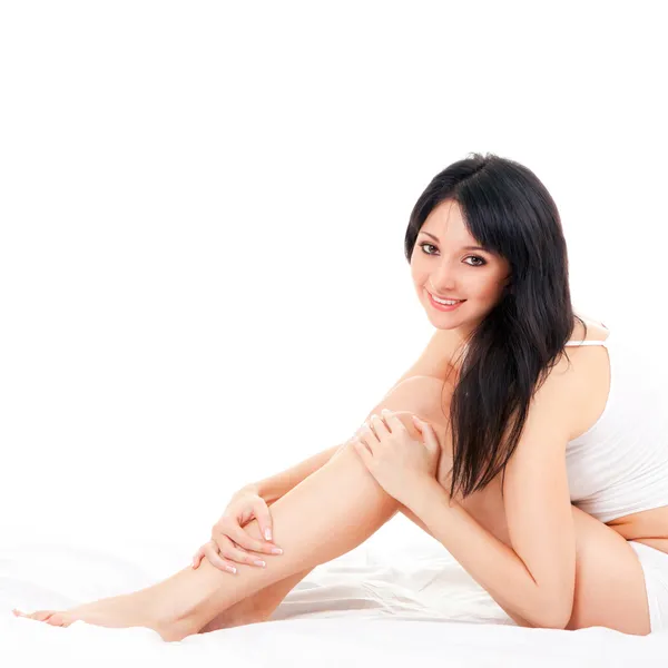 Ładny kobieta siedzi na łóżku biały — Zdjęcie stockowe