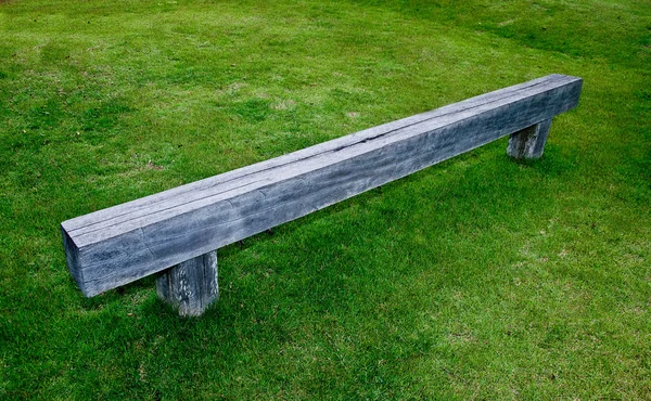 La panca in legno sul pavimento in erba verde — Foto Stock