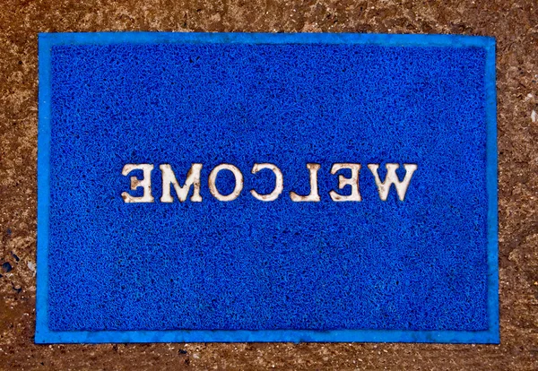 Η doormat της ευπρόσδεκτη κείμενο σε πάτωμα φόντο — Φωτογραφία Αρχείου