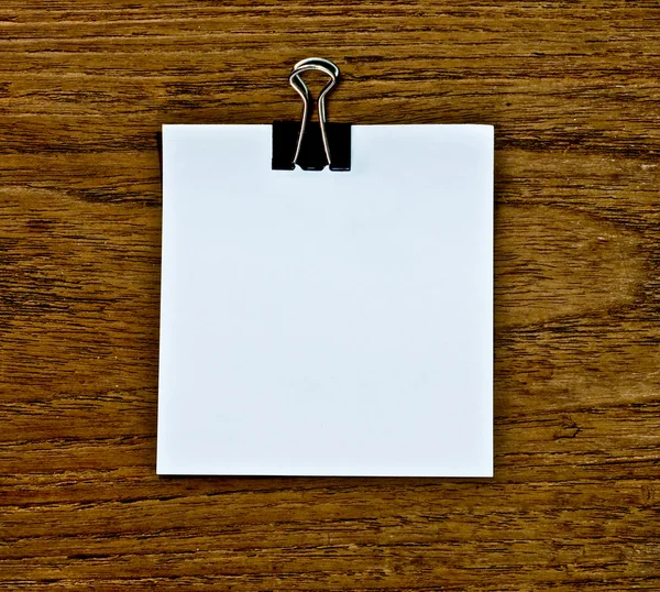 O clipe preto e papel branco nota em branco sobre fundo de madeira — Fotografia de Stock