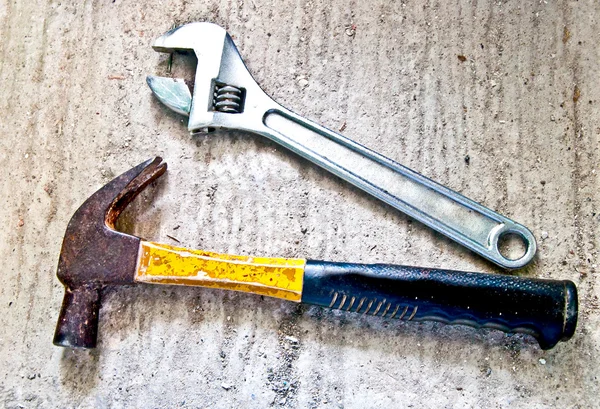El martillo y la llave inglesa en el suelo de cemento — Foto de Stock