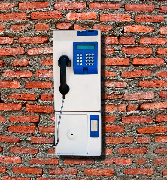 Veřejná telefonní izolovaných na cihlovou zeď na pozadí — Stock fotografie