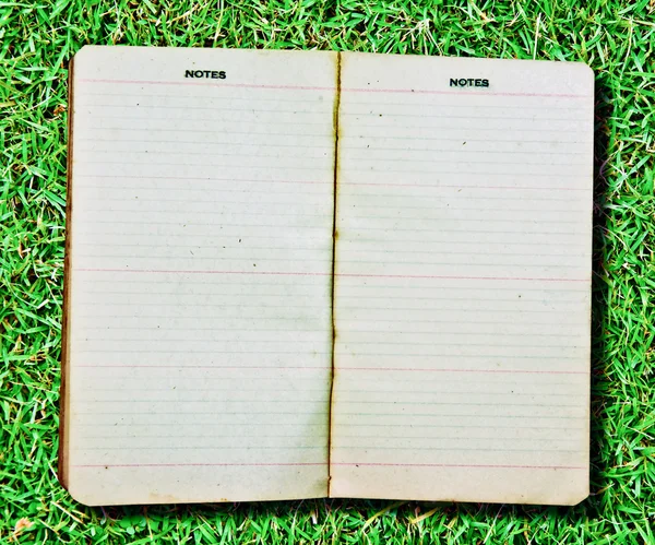 O caderno Vintage isolado no fundo de grama verde — Fotografia de Stock