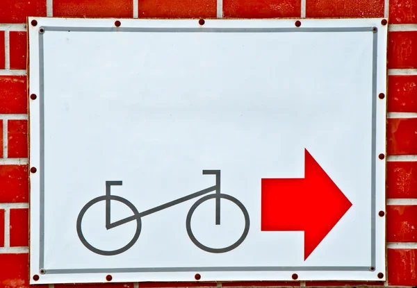 La guía de bicicleta de poste parque con flecha roja en el fondo de la pared de ladrillo — Foto de Stock