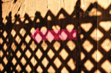 The Pink arrow with shadow of fence on wood floor clipart