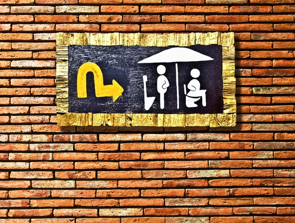 De gids post hout van toilet geïsoleerd op bakstenen muur achtergrond — Stockfoto