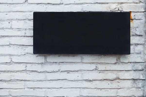 Czarny deska metalowe na mur z cegły — Zdjęcie stockowe