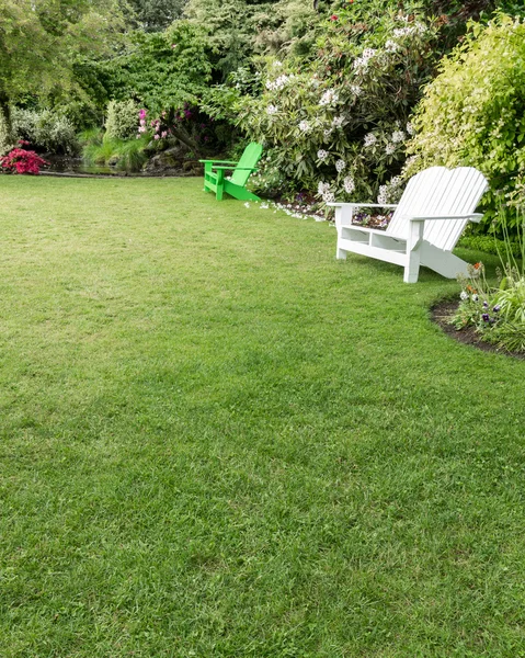Зеленая лужайка с цветами и стульями — стоковое фото