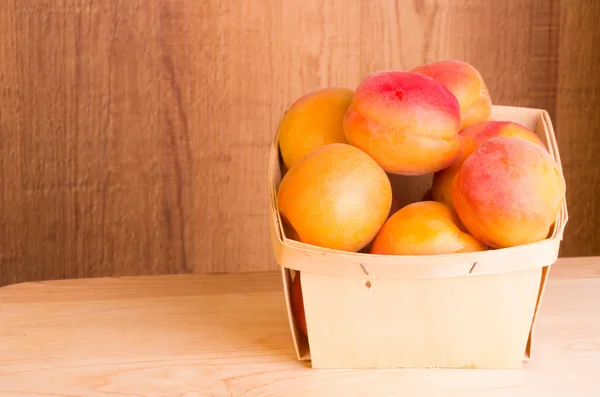 Färska aprikoser i korg — Stockfoto