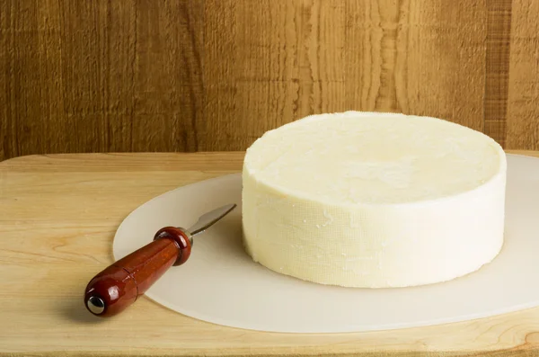 Круглый блок сыра с ножом — стоковое фото
