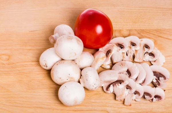 Mushrooms and tomato on wooden board — Stock Photo, Image