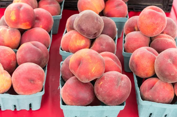 Korgar av persikor på bord — Stockfoto