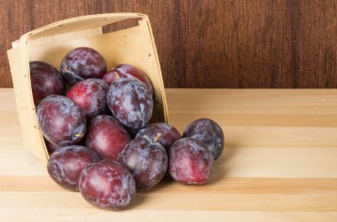 Prune plums spilling from wooden container