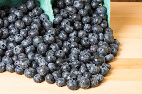 Blueberries spilling onto wooden table — Stock Photo, Image