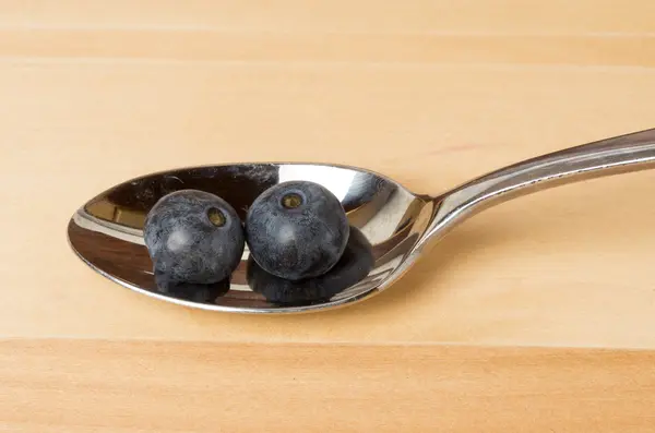 Two blueberries on a metal spoon — Stock Photo, Image