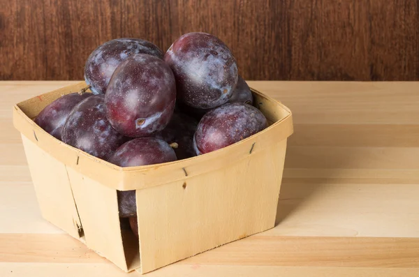 Container of prune plums on table — Stock Photo, Image