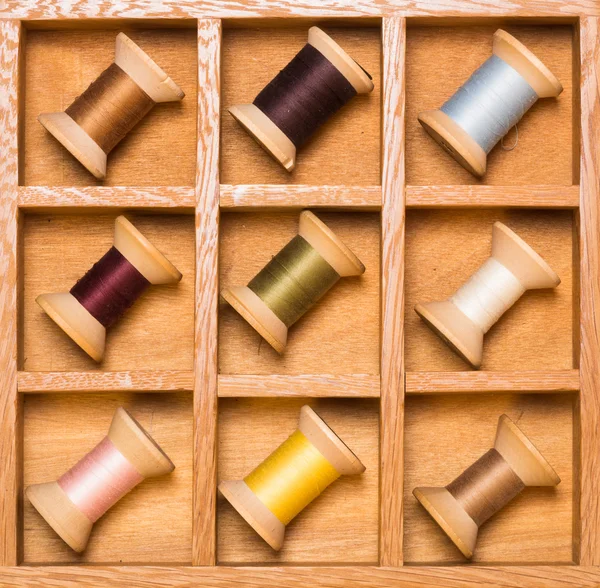 Wooden shadow box with wooden thread spools — Stock Photo, Image