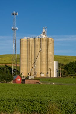 Cell tower and grain silo with green field clipart
