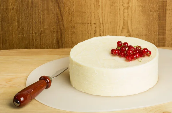 White cheddar cheese with knife and currants — Stock Photo, Image