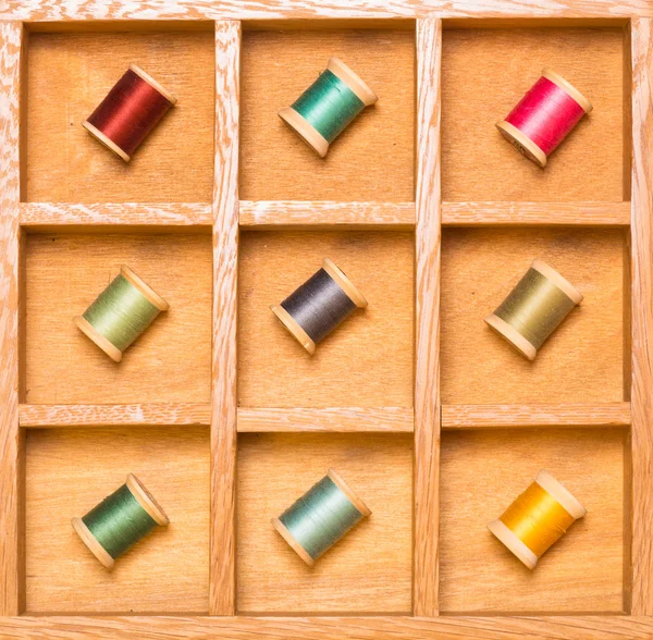 Thread spools in wooden shadow box — Stock Photo, Image