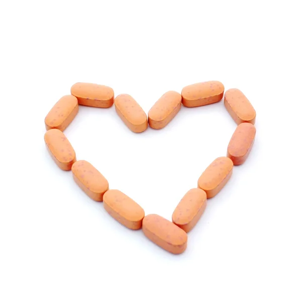 Orange pills in heart shape isolated on white background with co — Stock Photo, Image