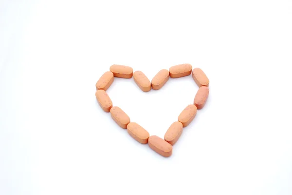 Pillole arancioni a forma di cuore isolato — Foto Stock