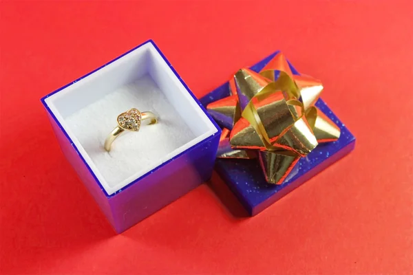 Anello a forma di cuore in una scatola di gioielli blu su sfondo rosso — Foto Stock