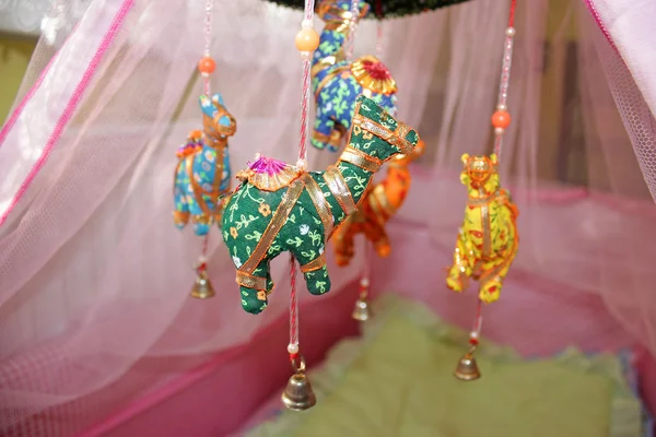 Brinquedos coloridos pendurados no berço com cortina de rede rosa horizontal — Fotografia de Stock