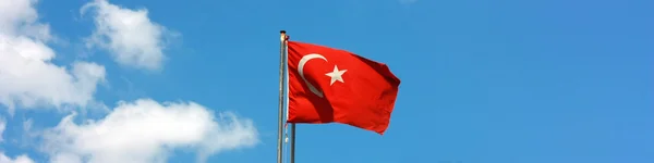 Türk bayrağı ile mavi gökyüzü ve bulutlar arkasında rüzgarda uçan. panoramik afiş — Stok fotoğraf