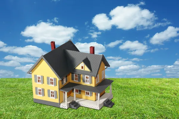 Modello casa su erba verde con sfondo cielo — Foto Stock
