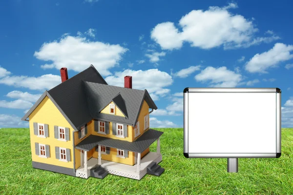 Model house on green grass with blank sign — Stock Photo, Image