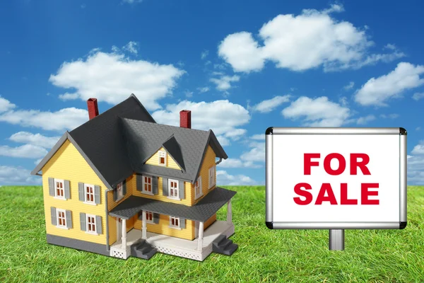 Model huis op groene gras met voor verkoop teken — Stockfoto