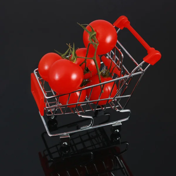 Ekologiska tomater i kundvagn isolerade på svart — Stockfoto
