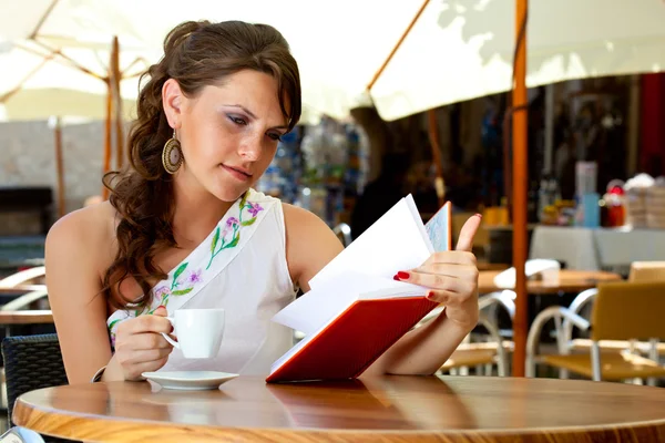 Jovem mulher está sentada no café — Fotografia de Stock