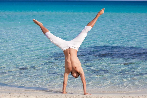 A man is standing upside down on the beach — Stock Photo, Image
