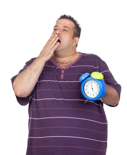 Gordo com um despertador azul bocejando — Fotografia de Stock