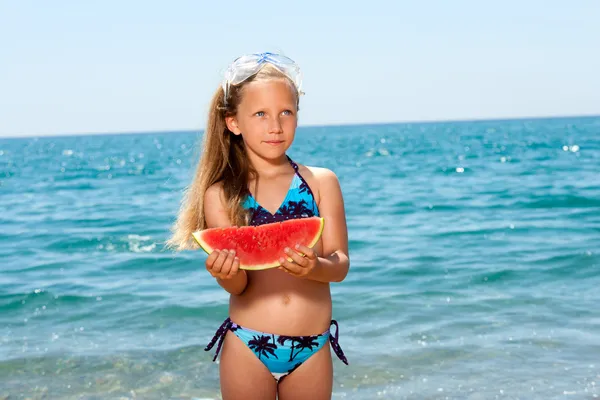 Χαριτωμένο κορίτσι τρώει καρπούζι στην παραλία. — Φωτογραφία Αρχείου
