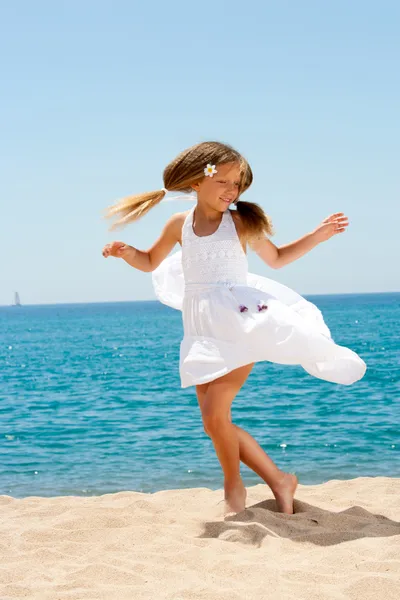 Leuk meisje in witte jurk dansen op het strand. — Stockfoto