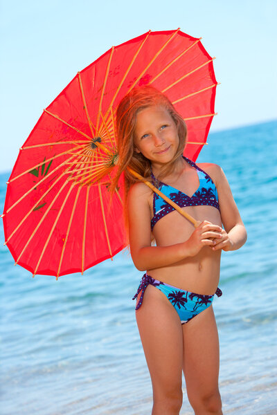 Portrait of young girl with umbrella on beach.
