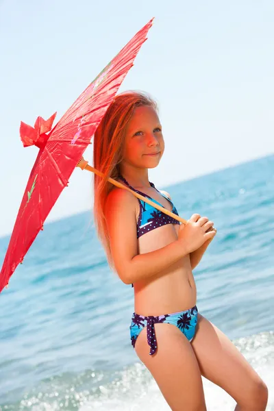 Słodka dziewczyna, chodzenie z parasolem na plaży. — Zdjęcie stockowe
