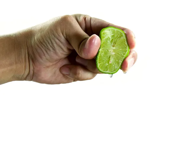 Hand squeezing juice from a green lime. — Stock Photo, Image