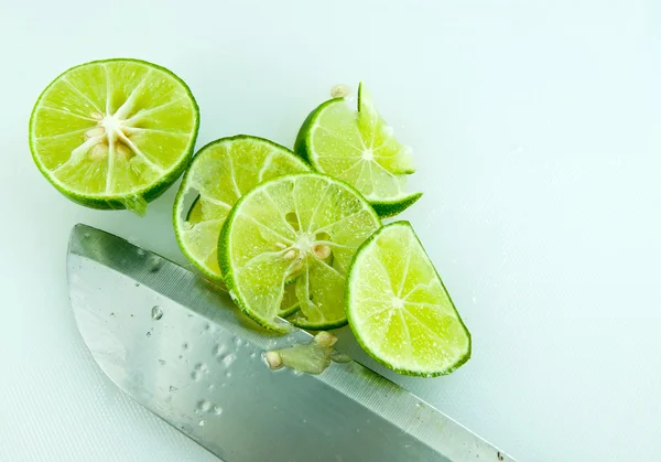 Limão fatiado e faca na placa de cozinha — Fotografia de Stock