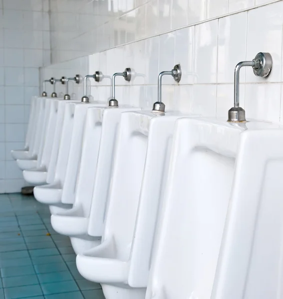Una fila de urinarios en la pared de baldosas en un baño público — Foto de Stock