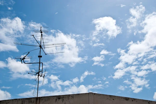 Home TV antennas mounted on a roof with blue sky