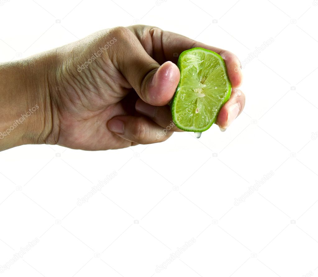 Hand squeezing juice from a green lime.