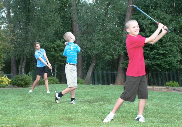 Três jovens golfistas - diversão em família Fotos De Bancos De Imagens